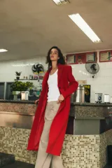 Abrigo largo de Zara confeccionado en mezcla de lana color rojo, con cuello de solapa, manga larga, bolsillos con solapa en el frente y cierre frontal de botones negros.
