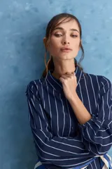 Camisa de calce relajado con cuello clásico, mangas largas con puños elastizados y rayas verticales que aportan un estilo atemporal. Su diseño liviano y versátil cuenta con estampado floral verde sobre fondo de rayas celestes y blancas.