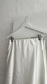 Pollera midi color blanco, de seda, con cintura elástica.