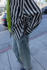 Camisa de cuello solapa con escote pico y manga larga. Presenta un bolsillo delantero de plastrón y bajo con aberturas laterales con cordones ajustables. Cierre frontal con botones.