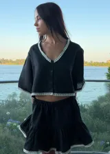 Falda corta de lino color negro, con diseño acampanado y detalle de puntilla blanca en el ruedo.