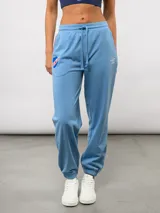 Pantalón de piqué recto color celeste, con pipings tricolor (rojo, blanco y azul) en los laterales. Incluye el escudo del Club Nacional de Football y el logo de Umbro bordados en el frente.