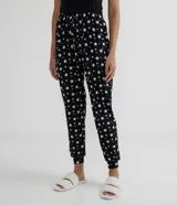Pantalón de pijama negro con estampado de estrellas blancas, cintura elastizada con cordón ajustable y tobillos ajustados.
