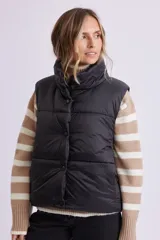 Chaleco de abrigo tipo puffer en color negro, con cuello alto, cierre frontal con cremallera y botones a presión.