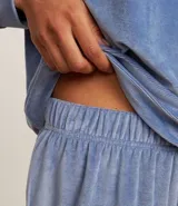 Pijama largo de dos piezas confeccionado en plush, compuesto por una blusa de manga larga con cuello redondo y un pantalón con cintura elástica y puños ajustados en los tobillos.