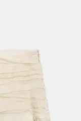 Falda midi confeccionada en hilatura con mezcla de lyocell, de tiro medio y cintura drapeada con forro interior combinado a tono. Presenta un diseño plisado con bajo recto y cierre lateral con cremallera oculta en costura.