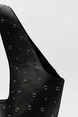 Bolso tipo tote negro de cuero sintético con micro tachas metálicas plateadas. Tiene asas integradas para llevar al hombro.