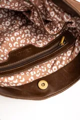 Cartera tipo bandolera de gamuza sintética color marrón, con asa larga decorada con nudos y detalles de herrajes metálicos dorados.