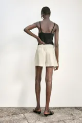 Bermuda color crema confeccionada en lino, de tiro alto con cintura elástica ajustable con cordones y bolsillos delanteros.