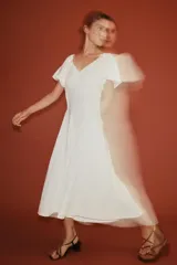 Vestido midi de color blanco, con escote en V y mangas cortas abullonadas.