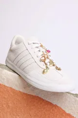 Zapatillas bajas color marrón con cordones y charms dorados.