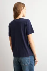 Remera azul marino de manga corta, corte recto y cuello redondo, con detalle de aplicación bordada de flores de crochet en el lateral inferior.