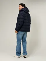 Campera puffer azul marino con diseño acolchado, capucha ajustable, cierre frontal de cremallera y bolsillos laterales con cierre. Presenta logo bordado en el pecho de Tommy Hilfiger.