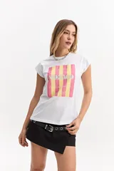 Musculosa oversize de algodón color blanco, con cuello redondo y diseño sin mangas con hombros ligeramente caídos. Presenta un estampado frontal rectangular con rayas verticales rosadas y amarillas, y la inscripción "MONACO".