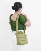 Bolsito tipo tote acolchado de color amarillo, con diseño de líneas horizontales y logo de la marca estampado en el frente. Cuenta con dos asas superiores acolchadas y una correa ajustable de cinta en color beige.