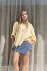 Camisa oversize amarilla de textura liviana, con cuello clásico, mangas largas y cierre frontal con botones.