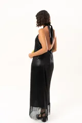 Vestido midi de satén color negro, con escote halter cruzado y ruedo terminado en flecos largos.