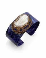 Pulsera tipo brazalete rígido con textura de piel de reptil en tonos grises y blancos. Presenta un aplique central ovalado decorado con una perla barroca rodeada de cristales y pequeñas perlas blancas.
