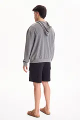 Campera con capucha y cierre frontal, color beige con efecto lavado stone wash, bolsillos tipo canguro y corte oversize.
