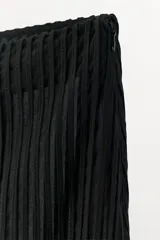 Falda midi de tiro medio en color negro, confeccionada con un diseño de tiras verticales combinadas a tono y bajo terminado en flecos largos. Incluye forro interior y cierre lateral con cremallera oculta.