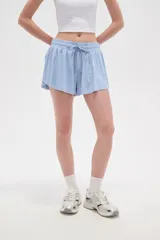Short de poliéster color celeste, de calce holgado y tiro alto, con cintura elástica ajustable mediante cordón y bolsillos laterales.