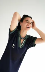 Remerón tejido de punto color azul marino con calados, cuello estilo camisa en verde oscuro con rayas blancas y verdes, y logo bordado en blanco en el pecho.