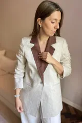 Blazer azul de lino con corte entallado, cuello y solapas combinadas en color gris, cierre con botón de nácar, bolsillos laterales y tajo en la espalda.
