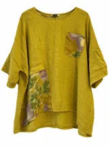 Blusa color mostaza con paneles de tela estampada floral en el bolsillo del pecho y en la parte inferior lateral, de manga corta y corte amplio.
