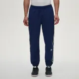 Pantalón de jogging azul marino con cintura y puños elásticos, bandas laterales estampadas con el logo de Umbro y sutil logo bordado en la pierna izquierda.