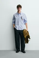 Camisa de corte regular fit confeccionada en tejido de algodón tipo Oxford. Presenta cuello abotonado, manga larga con puños abotonados, bolsillo frontal en el pecho y cierre de botonadura central.