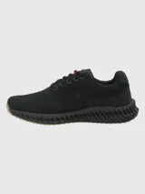 Sneaker de diseño deportivo con capellada de tejido knit negro, cordones al tono con detalle en rojo y suela con estructura tecnológica de amortiguación en color negro con base de goma clara.
