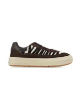 Championes de corte urbano confeccionados en gamuza marrón y detalles con estampado animal print tipo cebra en blanco y negro en los laterales y la puntera. Cuenta con cordones marrones y una suela plataforma de goma en tono marfil.