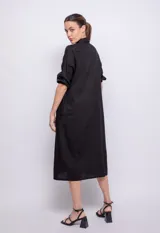 Vestido largo negro de lino y viscosa, abotonado al frente con alforzas en la parte central, mangas largas con elástico en los puños y cuello camisero.