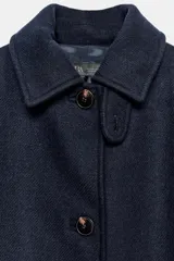 Abrigo de paño confeccionado en mezcla de lana, color azul marino. Presenta cuello solapa, manga larga, cierre frontal con botones y bolsillos delanteros. Incluye un cinturón del mismo tejido para ajustar a la cintura.