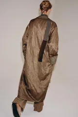 Kimono de la colección ZW de Zara, confeccionado en tejido marrón con acabado satinado. Presenta solapas anchas en tono verde con estampado estilo jacquard y flecos largos colgantes en el frente. Cuenta con mangas largas con puños estampados y bolsillos laterales ocultos.