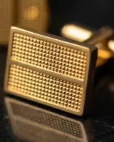 Gemelos rectangulares de acero con acabado dorado y textura estriada, diseñados para camisas de puño doble.