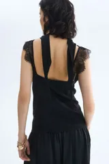 Top negro de tejido jacquard con leve brillo, escote en V y copas fruncidas. Presenta un panel transparente de encaje en el torso y ribetes de encaje decorativos en el escote y los breteles.