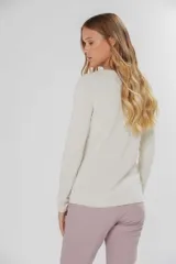 Buzo de tejido de punto fino con diseño de bloques de color en forma de zigzag en tonos lila y amarillo sobre base color crema. Presenta cuello redondo y mangas largas.