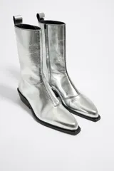 Botines camperos plateados de piel, con punta fina, tirador trasero y logo grabado en el lateral.