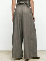 Pantalón de vestir de corte sastrero, tiro alto y pierna ancha. Presenta un diseño de rayas verticales finas en tono grisáceo y cuenta con pinzas en la cintura para un ajuste estructurado.