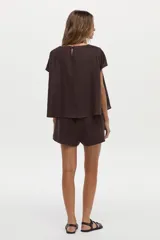 Blusa de lino color blanco, con cuello bote y mangas cortas de corte holgado.
