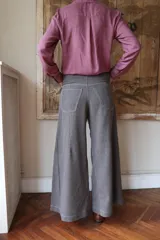 Pantalón de corte wide leg en color marrón, con tiro medio, cierre frontal con botón metálico y costuras visibles a contratono.