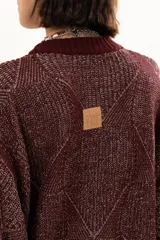 Buzo de punto color vino con diseño de trama geométrica, cuello redondo, mangas largas con puños ajustables mediante cordones y terminaciones acanaladas.