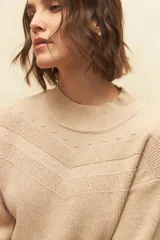 Polera de tejido de punto color beige con cuello alto y diseño de texturas en el frente con patrón en chevron y detalles de puntos en relieve.