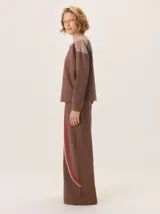 Pantalon de pierna ancha color marron, con detalles de franjas laterales en tonos beige y rojo. Cuenta con cintura elastizada y bolsillos traseros.