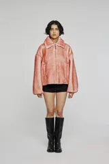 Campera corta de pelo sintético en color rosado, con diseño de volumen amplio, cuello estructurado y cierre frontal con cremallera. Cuenta con bolsillos laterales integrados.