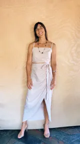 Pollera midi envolvente de lino y viscosa, con diseño de capas curvas y detalle de frunces laterales con lazo ajustable en la cintura.