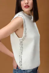 Chaleco de punto color bordó, con cuello redondo y diseño sin mangas. Presenta detalles de apliques de brillos en los laterales frontales.