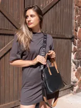 Cartera negra de cuero genuino con correa corta de cuero color tostado y correa larga de cinta negra con letras blancas.