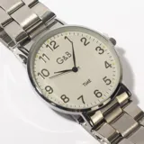 Reloj de pulsera plateado con esfera blanca, números arábigos negros y agujas negras.